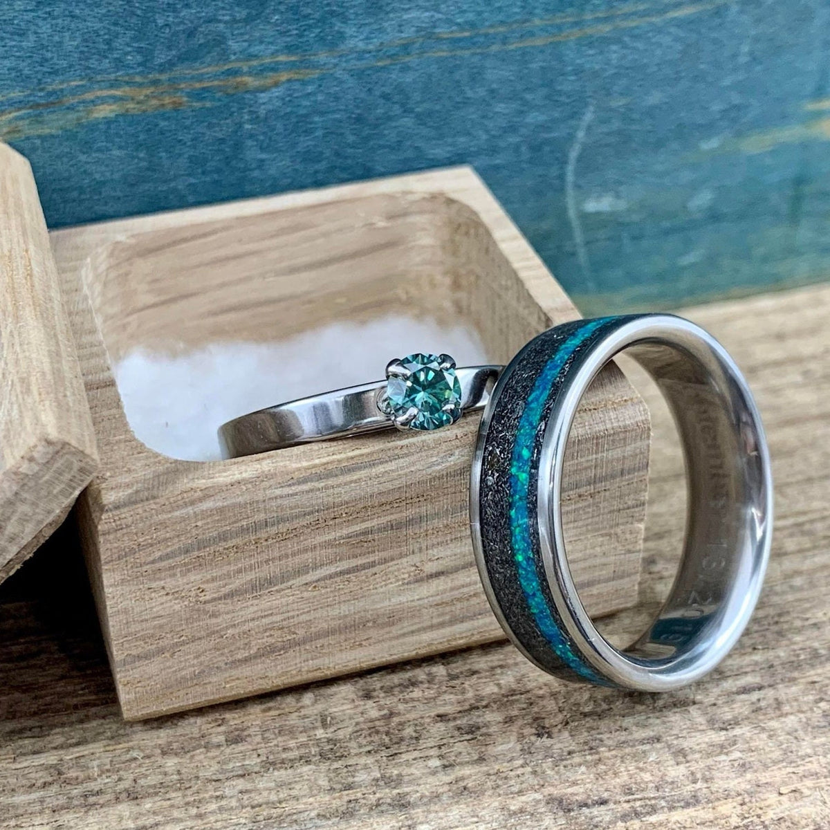 His and hers meteorite wedding band set with moissanite engagement ring, featuring sleek metal bands and sparkling gemstones.